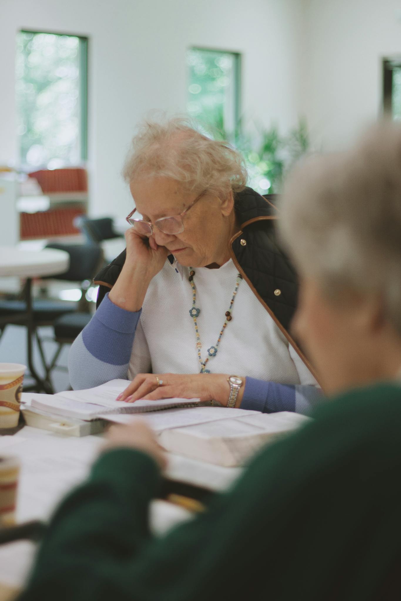 Elderly women participating in an indoor Bible study group session, fostering community.